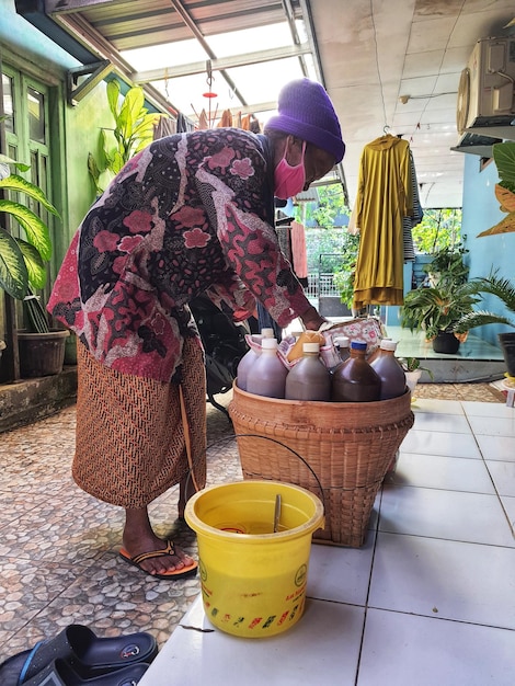 Jepara Indonesia in July 2022 A grandmother selling herbal medicine is preparing a customer39s order