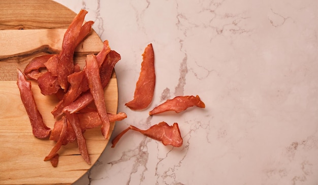 Jerky chicken meat chips on a light marble background