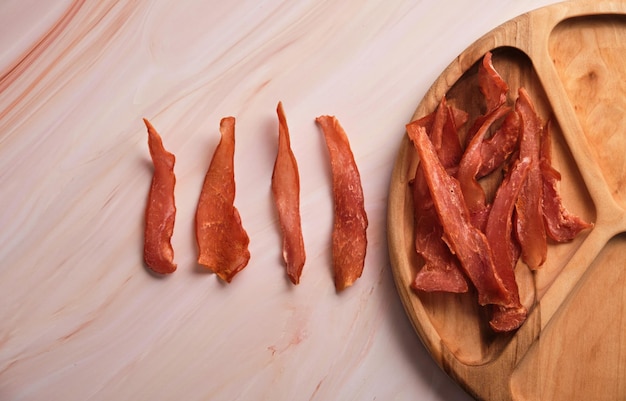 Jerky chicken meat chips on a light marble background