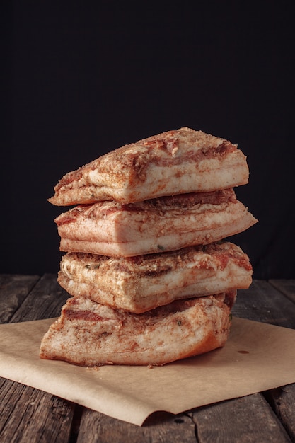 Lardo a scatti quattro pezzi. la trama fibrosa del bacon e delle spezie è chiaramente visibile. prodotti a base di carne e strutto sono sul bancone.