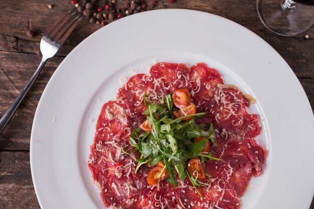 Jerky with cherry tomatoes and arugula on rustic wooden table