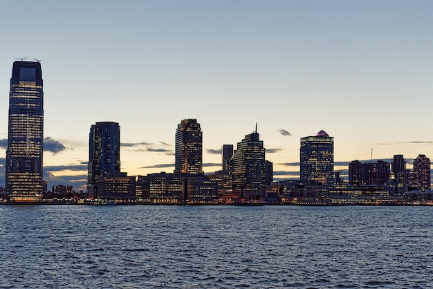 Jersey City skyline with skyscrapers at night over Hudson River viewed from New York City Manhattan downtown