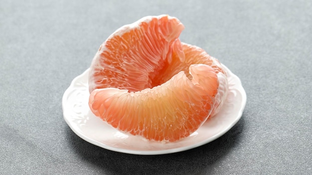 Jeruk Bali Balinese Pomelo Grapefruit on White Plate Isolated on Grey Table Close Up