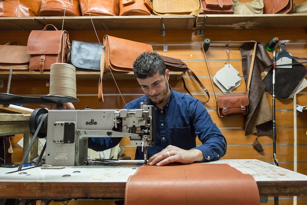 Jerusalem, Israël - 16 november 2016: in Israël gevestigde mannelijke lederen ambachtsman die op maat gemaakte leren tassen maakt in een kleine winkel in de oude stad van Jeruzalem, Israël.