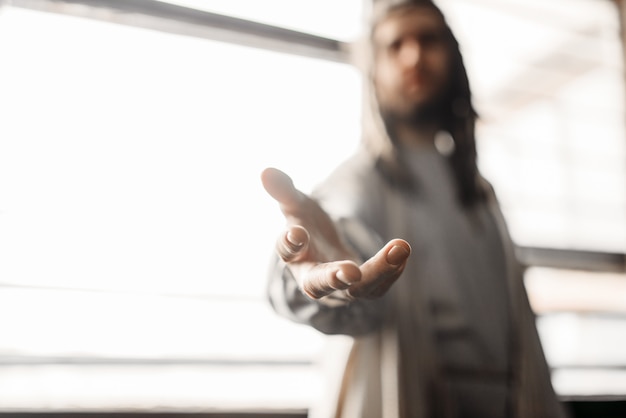 Photo jesus christ in white robe reaching out his hand. son of god, christian faith symbol