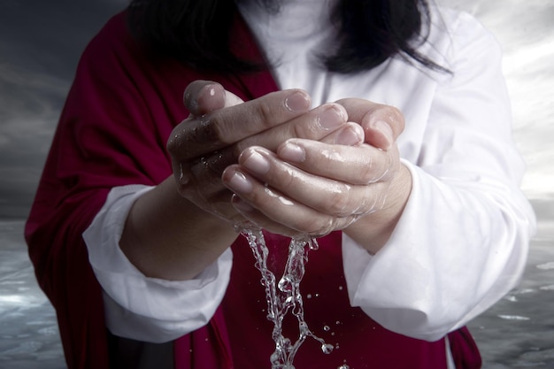 Foto gesù cristo con il palmo aperto che tiene l'acqua con uno sfondo drammatico