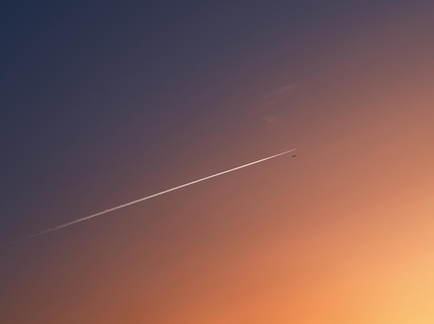 Foto jet plain vliegt in de zonsondergang diagonale uitlaat spoor