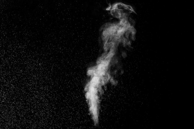 A jet of white water vapor with splashes of water from the humidifier Isolated on a black background