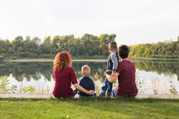 Jeugd en natuur concept - gezin met zoontjes zittend op het groene gras