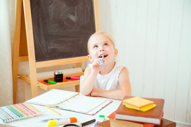 Jeugd en terug naar school-concept. meisje met doordachte gezichtsuitdrukking doet huiswerk