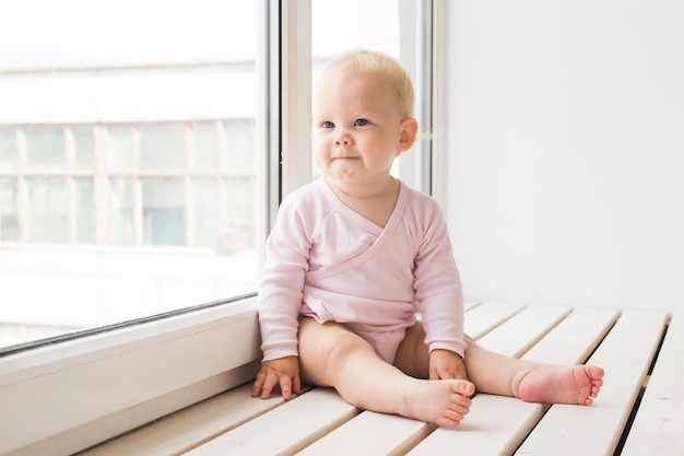 Jeugd, familie en zuigeling concept - Babymeisje op de vensterbank thuis