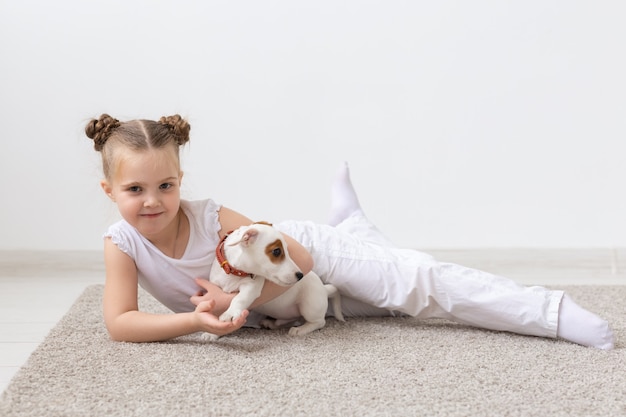 Jeugd, huisdieren en honden concept - klein kind meisje poseren op de vloer met puppy.