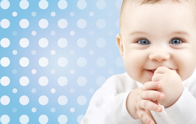 jeugd, mensen en geluk concept - lachend gezicht van de babyjongen over blauwe en witte stippen patroon achtergrond
