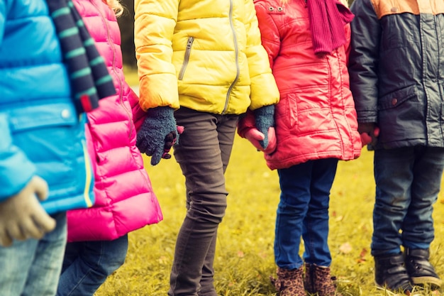 jeugd, vrije tijd, vriendschap en mensen concept - close-up van gelukkige kinderen hand in hand in herfst park