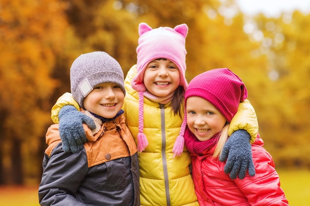 jeugd, vrije tijd, vriendschap en mensen concept - groep gelukkige kinderen knuffelen in herfst park