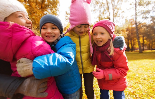 jeugd, vrije tijd, vriendschap en mensen concept - groep gelukkige kinderen knuffelen in herfst park