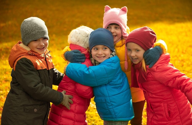 jeugd, vrije tijd, vriendschap en mensen concept - groep gelukkige kinderen knuffelen in herfst park