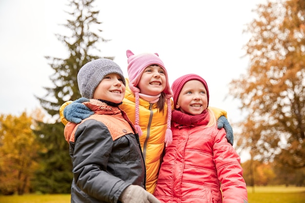 jeugd, vrije tijd, vriendschap en mensen concept - groep gelukkige kinderen knuffelen in herfst park