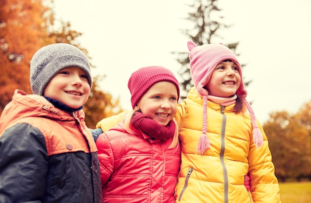 jeugd, vrije tijd, vriendschap en mensen concept - groep gelukkige kinderen knuffelen in herfst park