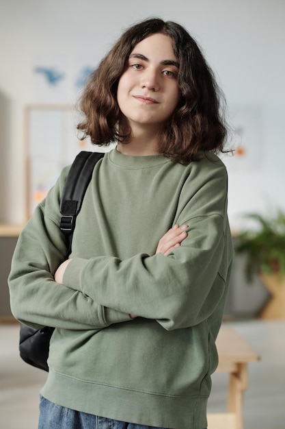 Jeugdige middelbare scholier in grijze sweater die in de klas staat