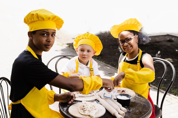 Jeugdkookactiviteit van multinationale kinderen van zwarte Afrikaanse en blanke kinderen Gelukkig gezelschap van multi-etnische kinderen die deeg koken