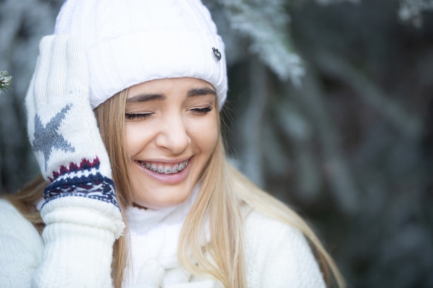 Jeugdmeisje met bretels houdt haar hoofd lachend op een koude winterdag in de natuur.