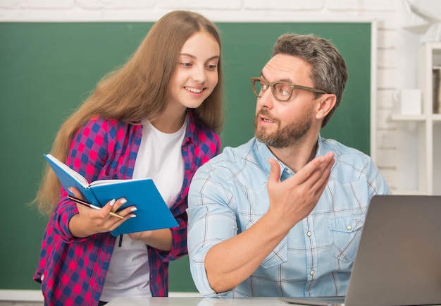 Jeugdonderwijs vrolijke leerling en tutor met laptop vader en tienermeisje studeren privéleraar en kind houden beurt vast familie helpen vader en dochter notebook gebruiken terug naar school