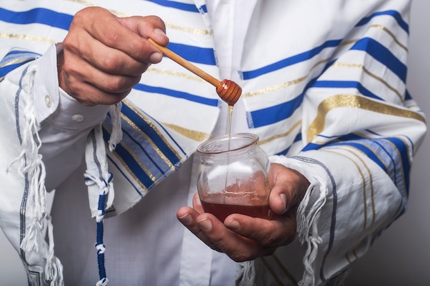 사진 tallit, 기도 숄에 싸인 유대인 남자. 유태인 새해인 로시 하샤나에 사용되는 유리 항아리 위에 나무 꿀 국자를 들고 있는 남자. 배경 이미지 꿀 항아리와 국자