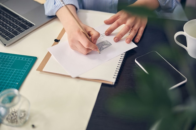 Jewel designer creating a product sketch on paper while using a pencil