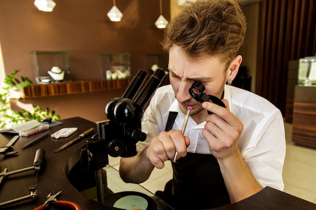 The jeweler examines the gem under the magnifying glass