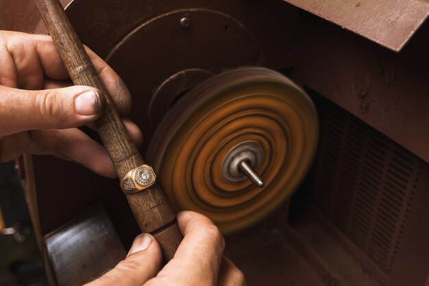Jeweler polishes a gold ring on a special machine in a workshop