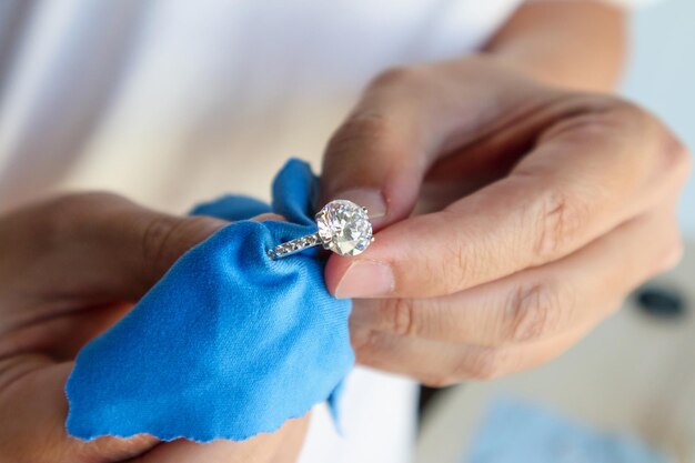 Photo jeweller hand polishing and cleaning jewelry diamond ring with micro fiber fabric