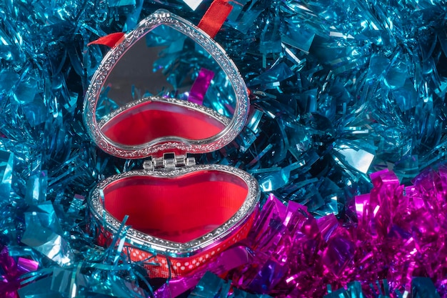 jewelry box in the form of a heart on a background of tinsel