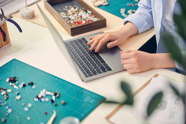 Photo jewelry employee working on laptop while searching information via the internet