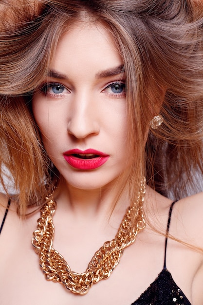 Jewelry, holidays, luxury and people concept - Beautiful female face with natural perfect skin. Gold Woman skin. Gold earrings, ring and necklace. Cosmetics, beauty and manicure on nails