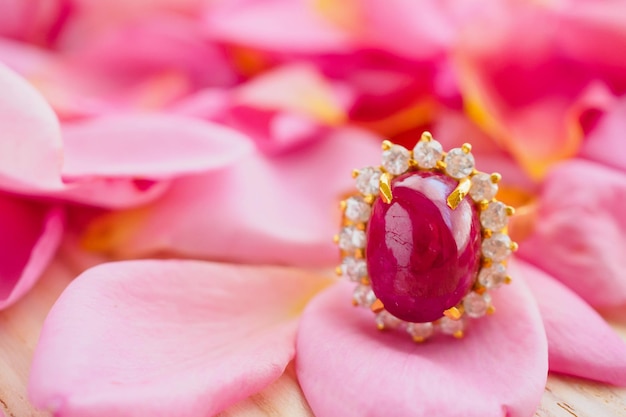 Anello di rubino rosso dei gioielli con un bellissimo sfondo di petali di rosa rosa da vicino