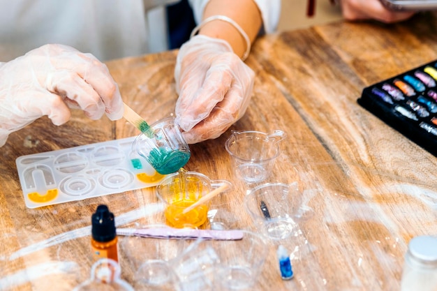 Laboratorio di gioielleria con resina epossidica primo piano di una mano di  donna che versa resina liquida colorata