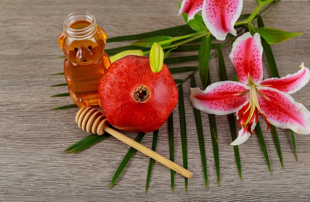 Jewish food, Jewish Holiday, Holiday symbol, rosh hashanah jewesh holiday concept - pomegranate honey pink lilies over wooden table. traditional