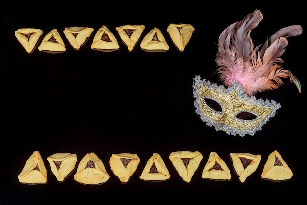 Jewish holiday background with hamantaschen cookies and carnival mask for Purim. Copy space.