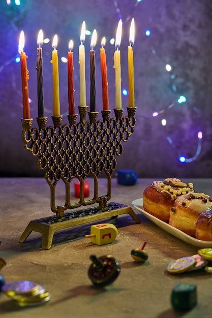 Jewish holiday Hanukkah. A traditional dish is sweet donuts. Hanukkah table setting a candlestick with candles and spinning tops