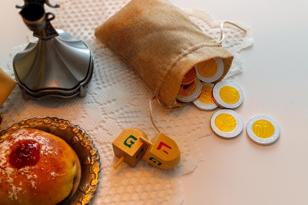 Jewish holiday hanukkah with donuts and wooden dreidels\
spinning top chocolate coins top view