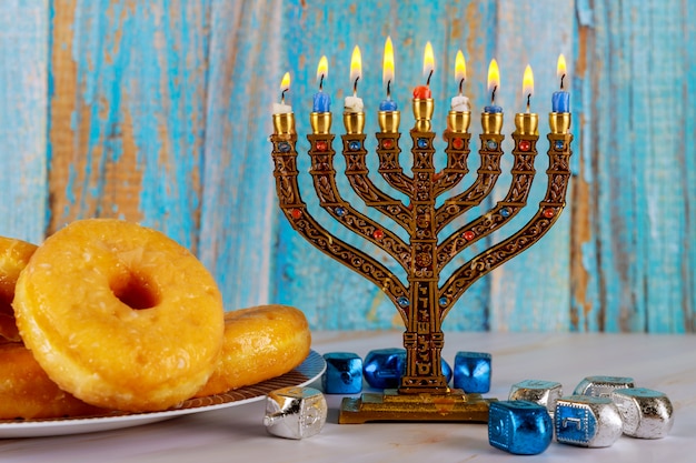 Jewish holiday hanukkah with menorah, donuts and dreidels