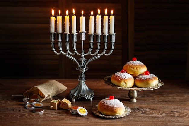 jewish holiday hanukkah with menorah traditional candelabra donuts and wooden dreidels spinning top chocolate coins
