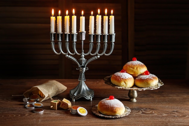 Jewish holiday Hanukkah with menorah traditional Candelabra donuts and wooden dreidels spinning top chocolate coins