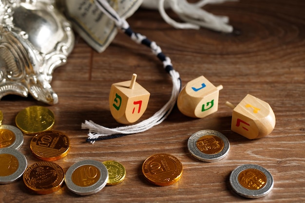 Еврейский праздник Ханука с деревянными дрейдлами, крутящими шоколадные монеты на деревянном фоне
