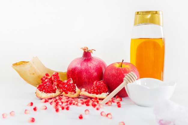 Jewish holiday Rosh Hashanah Apples Honey and Pomegranate on the White Table Copy space