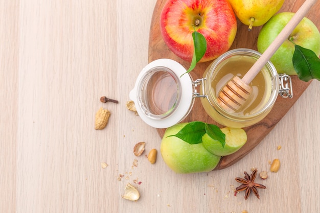 Jewish holiday Rosh Hashanah background with honey and apples on wooden table.