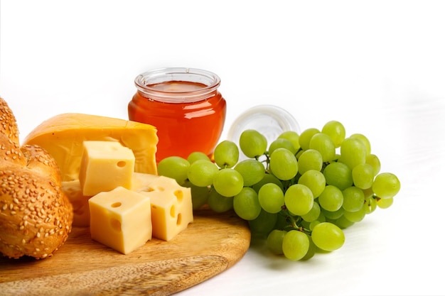 Jewish holiday Shavuot concept with pieces of cheese bread grape honey on wooden board