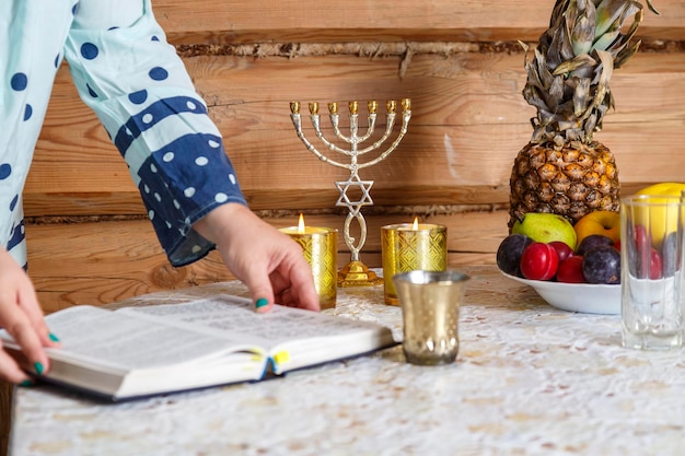 Photo a jewish woman after lighting candles reads the bondage of shabbat according to the siddur