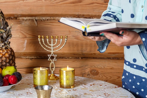 A Jewish woman after lighting candles reads the evening prayer of maariv according to the siddur